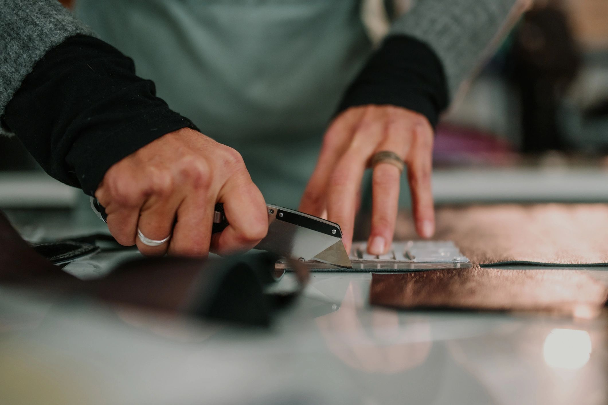 Hands measuring and cutting material on a workbench