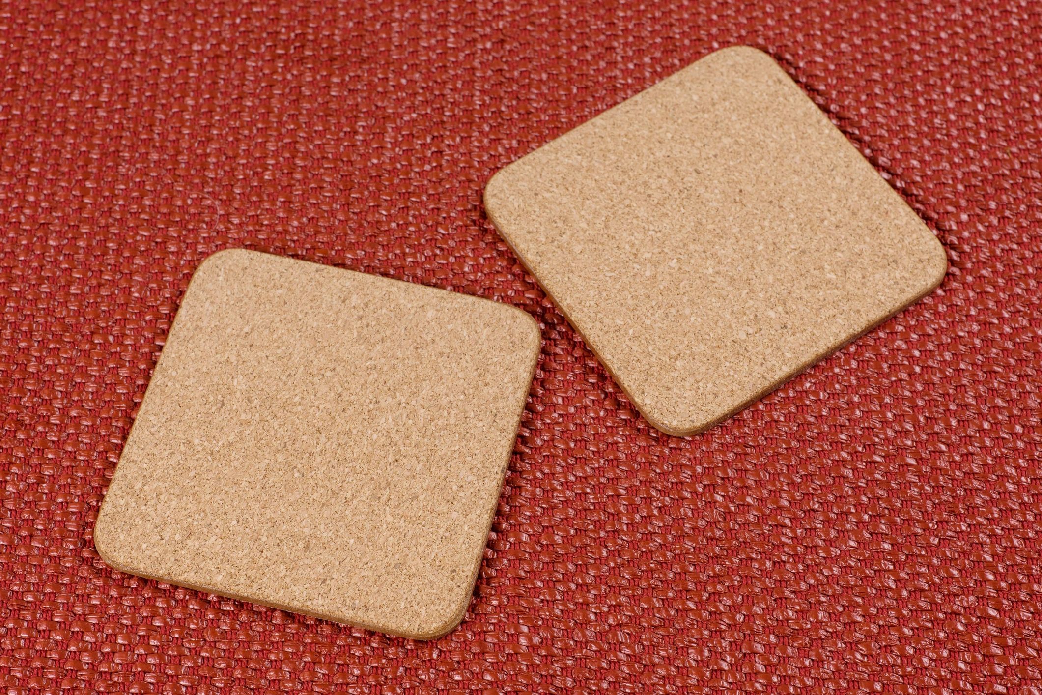 Two square cork stands on a textured terracotta background